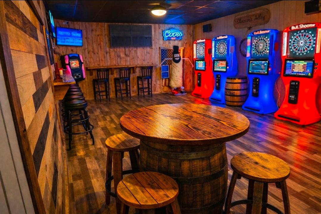 Lucky's game room with dart machines, barrel table, and wood-paneled walls
